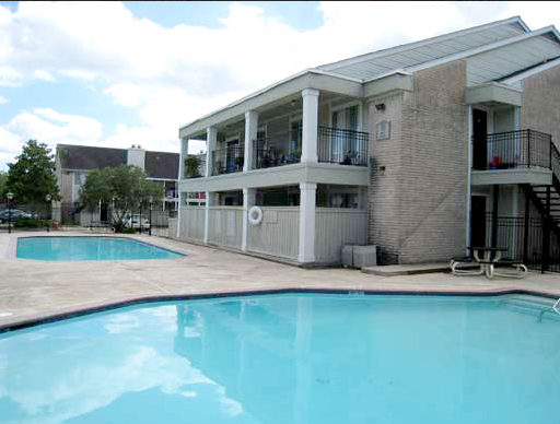 a large apartment building with a large swimming pool in front of it .