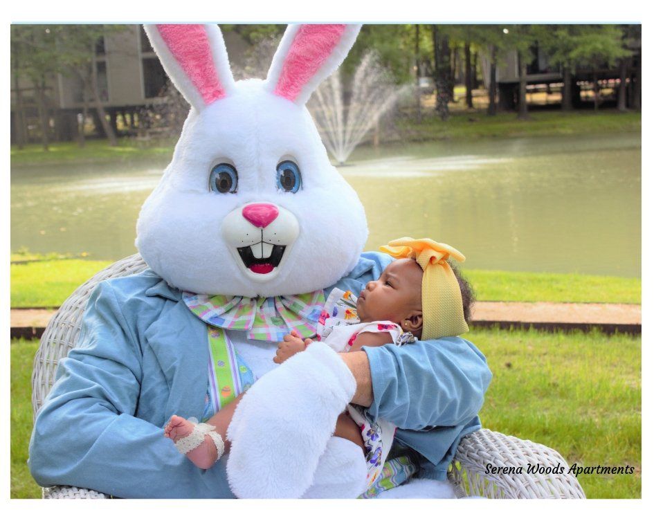 A person dressed as an easter bunny is holding a baby.