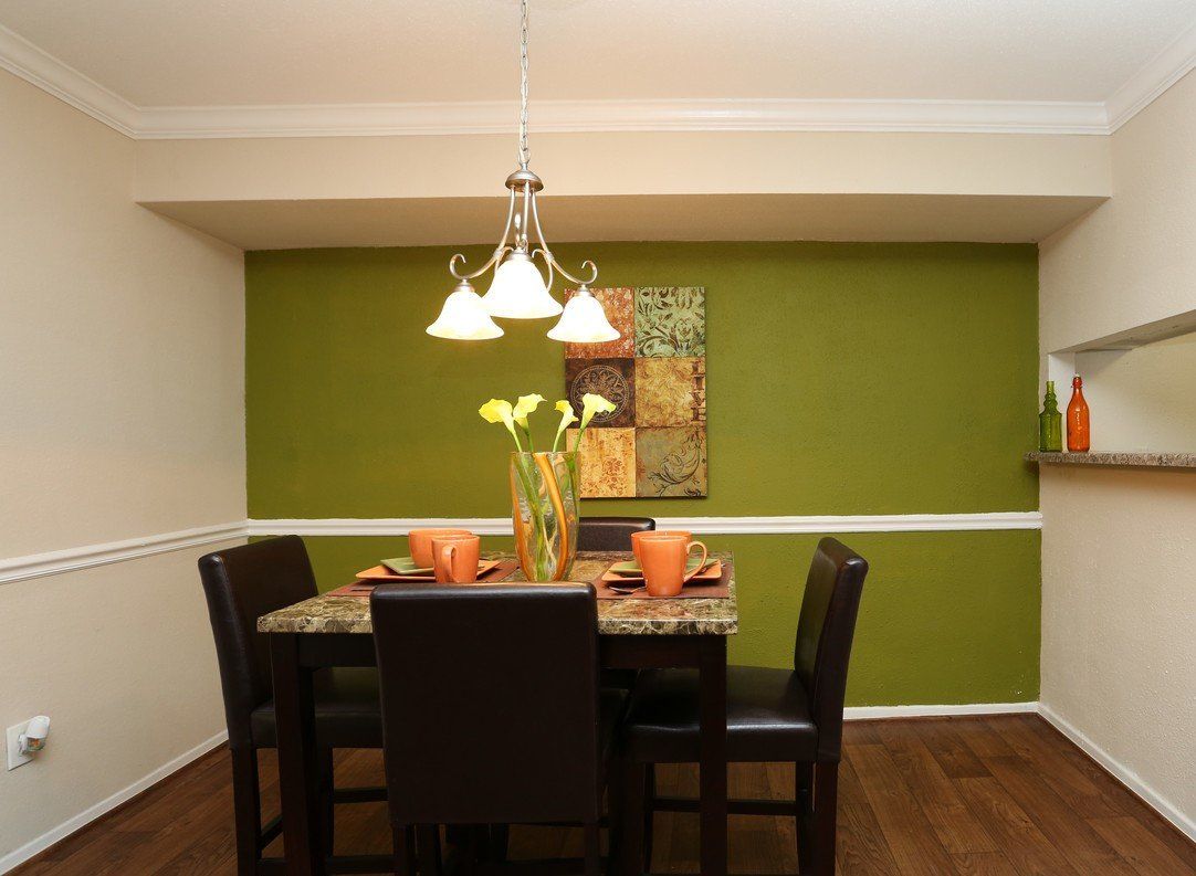 a dining room with a table and chairs and a green wall