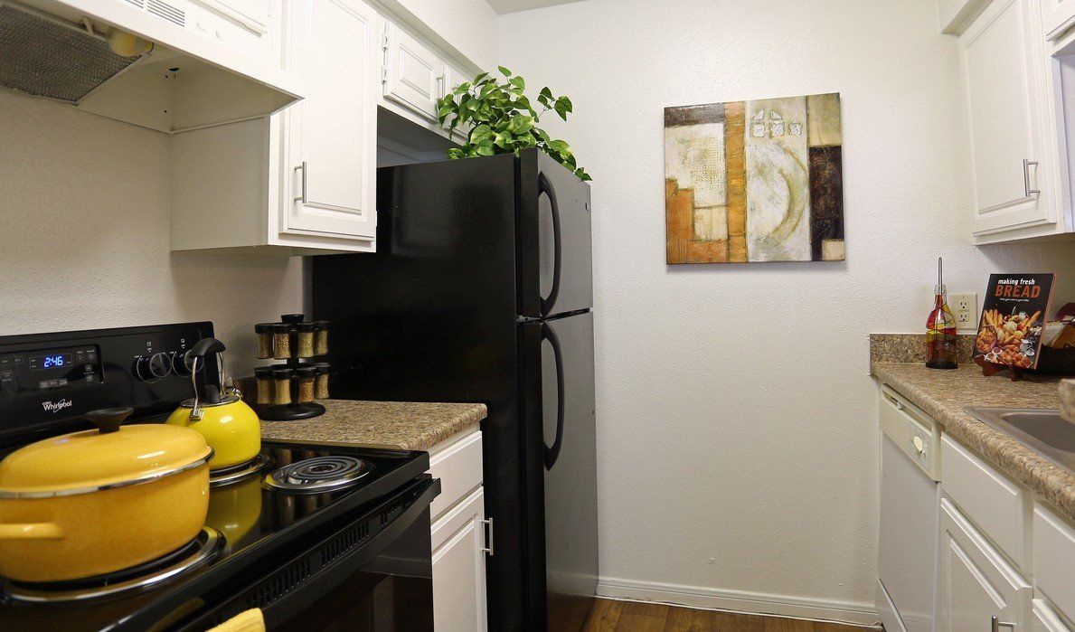 a kitchen with a black refrigerator and white cabinets at Breckenridge at Cityview.