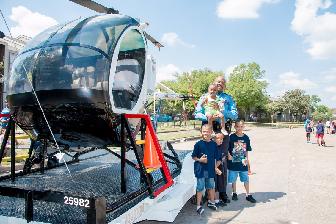 A man and three children are standing in front of a helicopter.