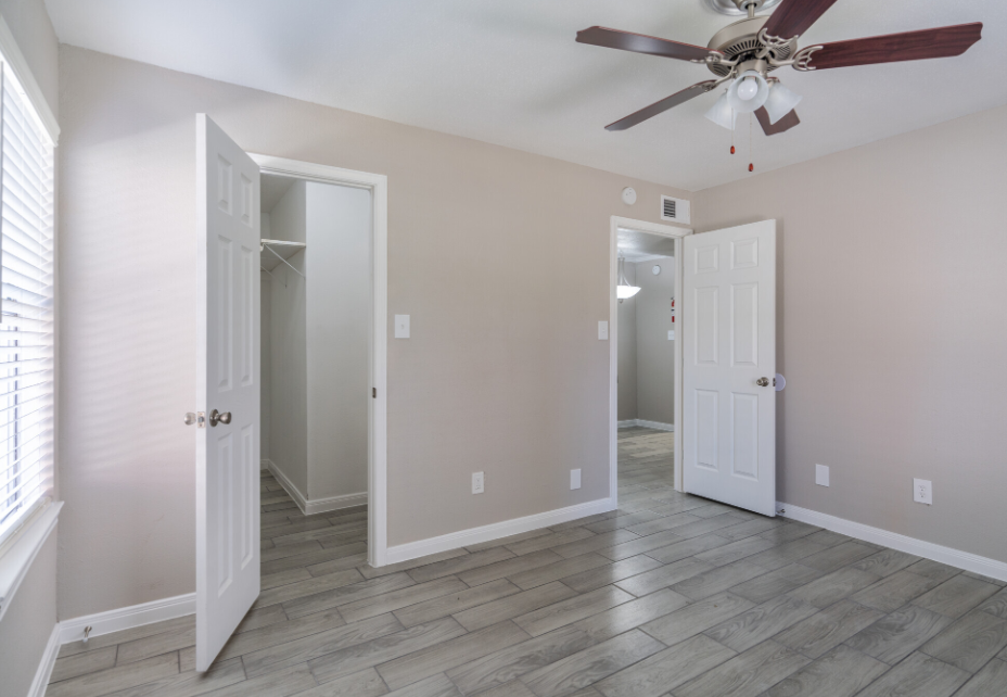 An empty bedroom with a ceiling fan and a closet.