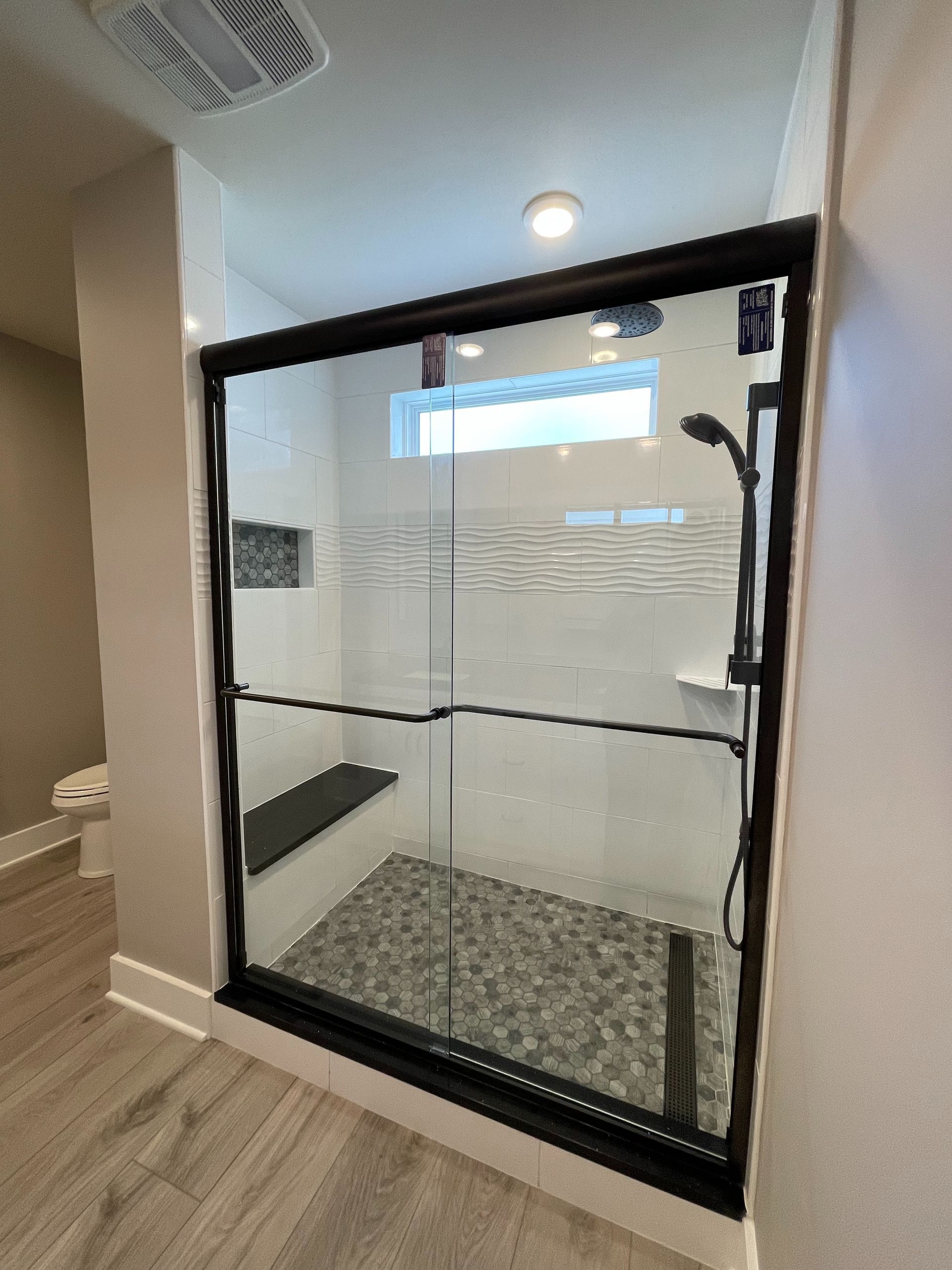 A bathroom with a walk in shower with a black frame.