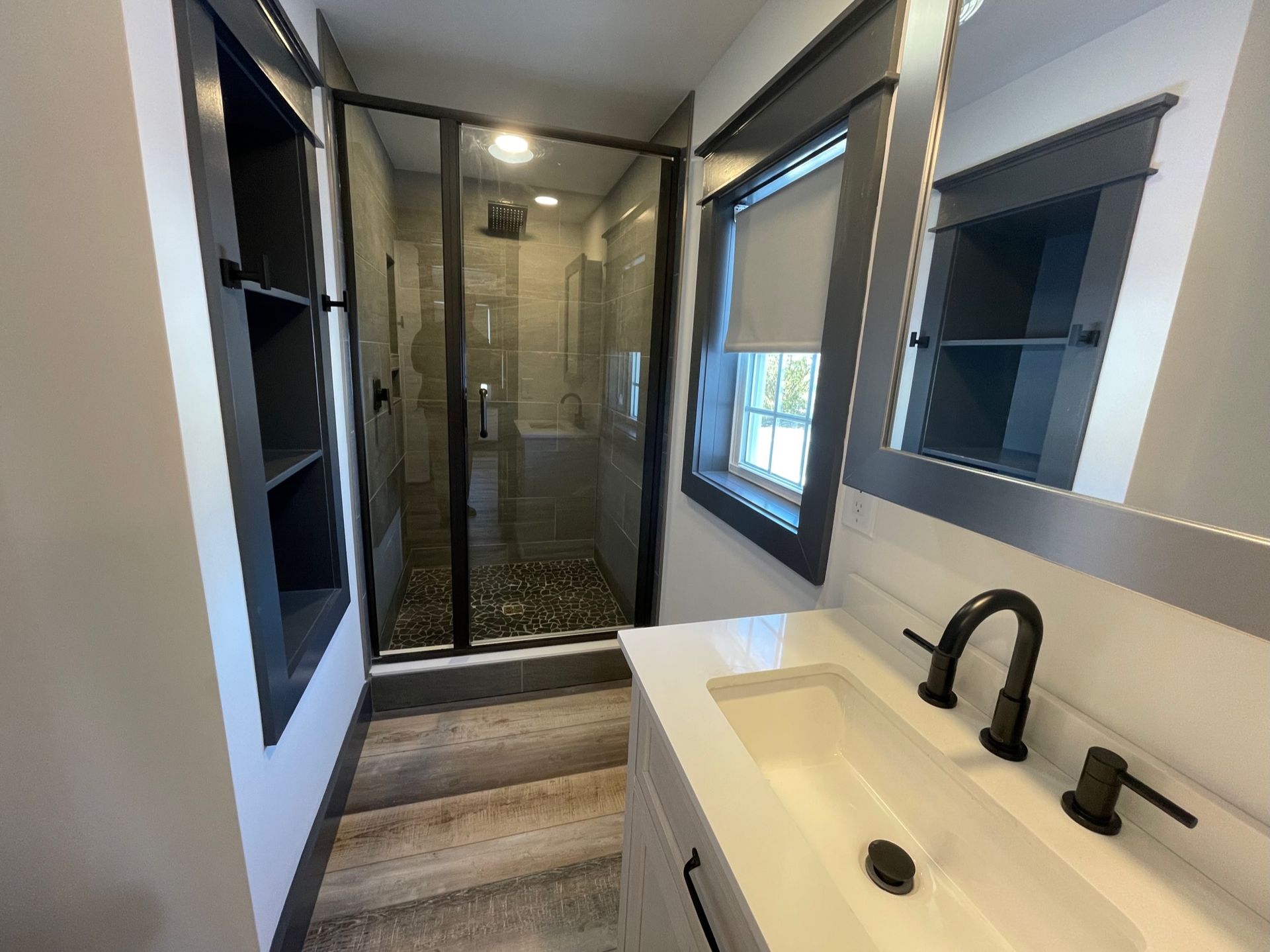 A bathroom with a sink , mirror and walk in shower.