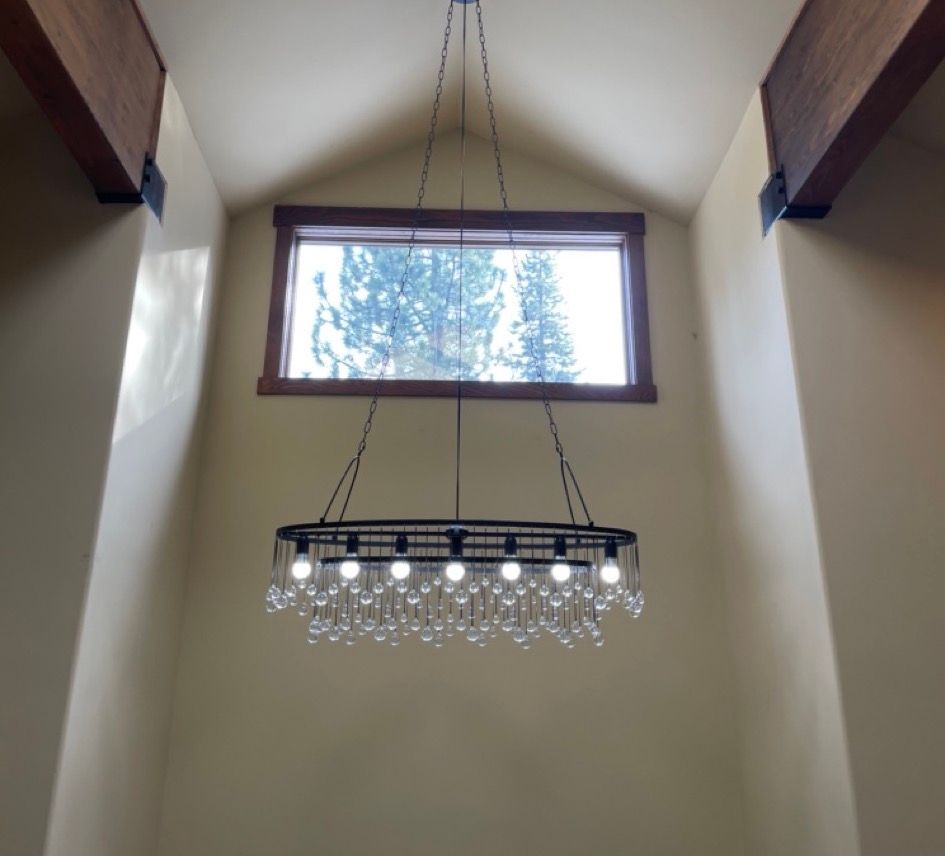 A chandelier hangs from the ceiling in front of a window