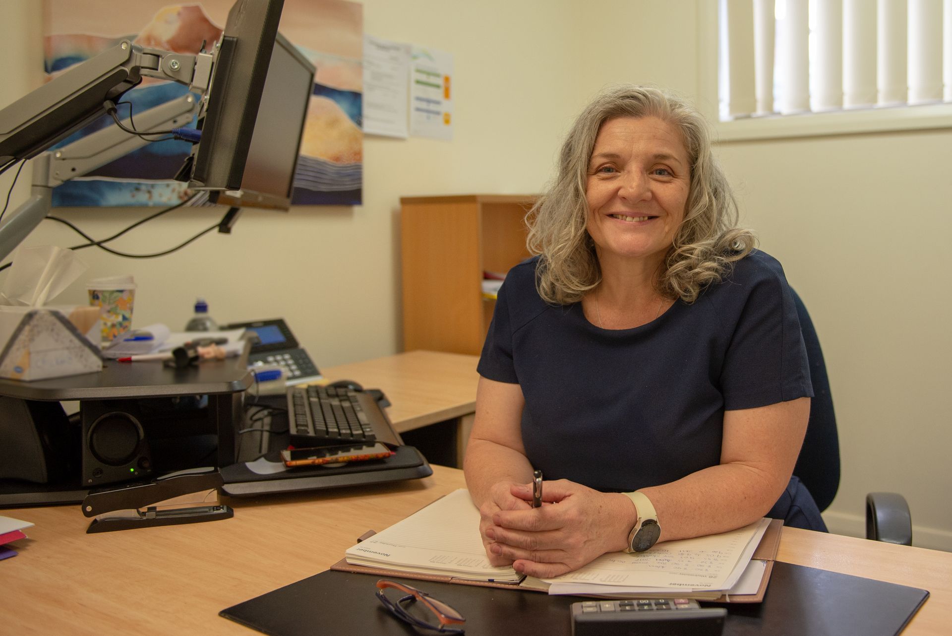 Woman smiles, sitting at desk in an office setting — Wright Partners in Dubbo, NSW