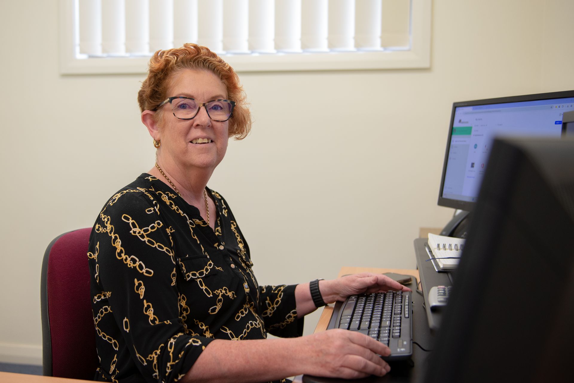 Woman with glasses working at computer in an office, smiling — Wright Partners in Dubbo, NSW