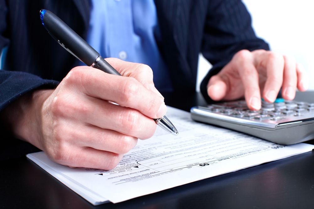 Person Filling out Paperwork with A Pen and Calculator — Wright Partners in Dubbo, NSW