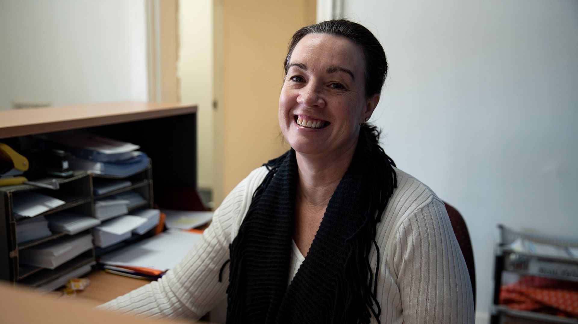 Woman Smiles Behind a Desk in A Well-Lit Office Setting — Wright Partners in Dubbo, NSW