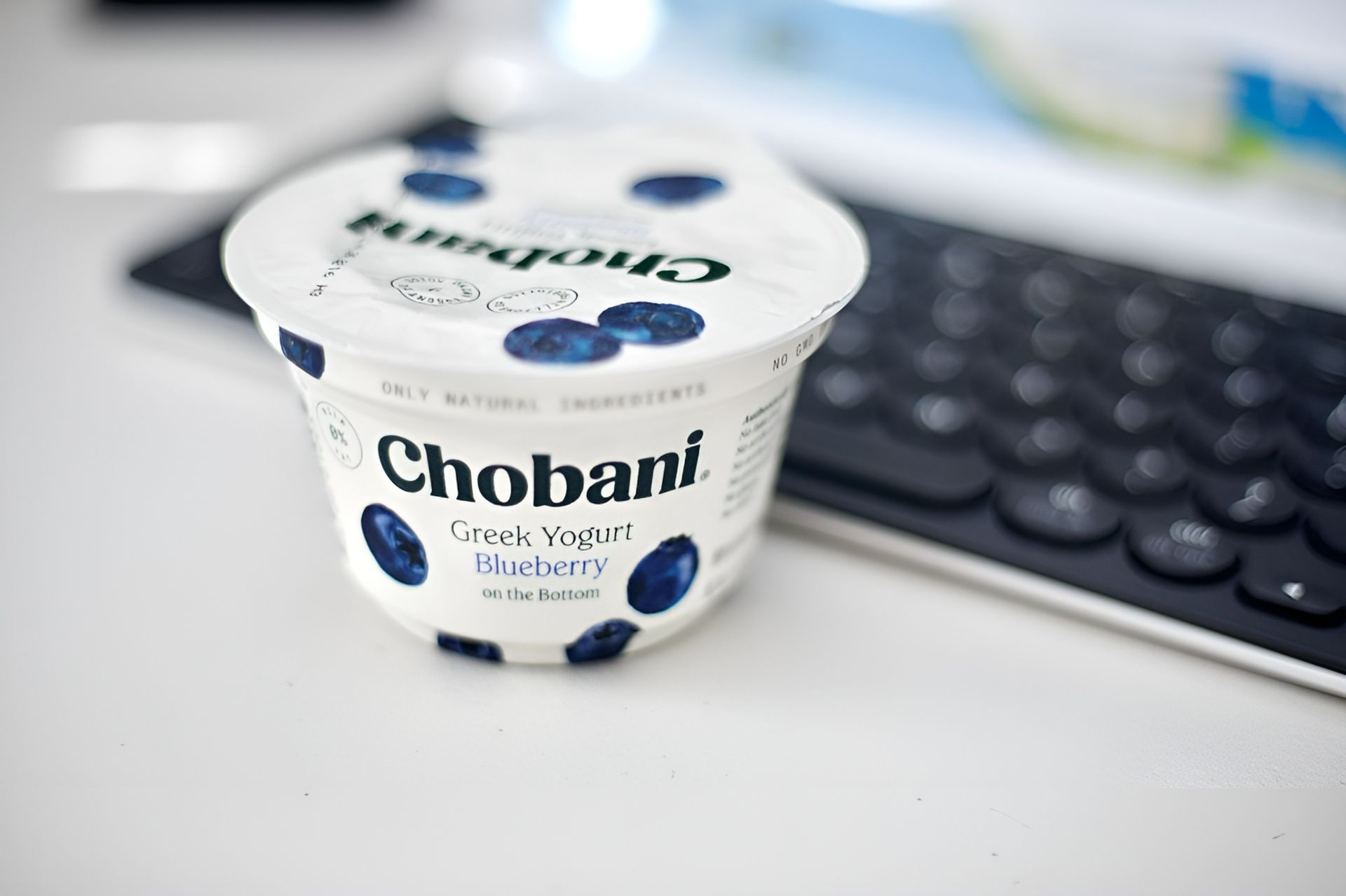 Chobani Blueberry Greek Yogurt Cup on A White Surface Next to A Black Keyboard — Wright Partners in Dubbo, NSW