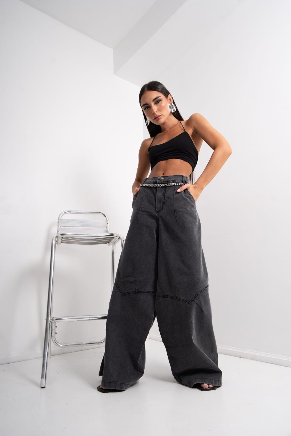 Mujer con pantalones negros y un top de tubo de color amarillo neón posando en un estudio.