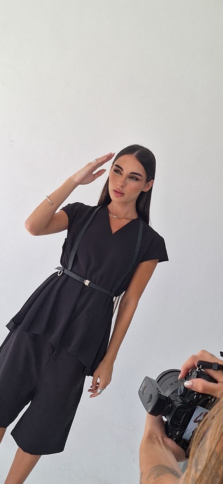 Una mujer vestida de negro posa para una foto. Saluda y un fotógrafo le toma una foto.