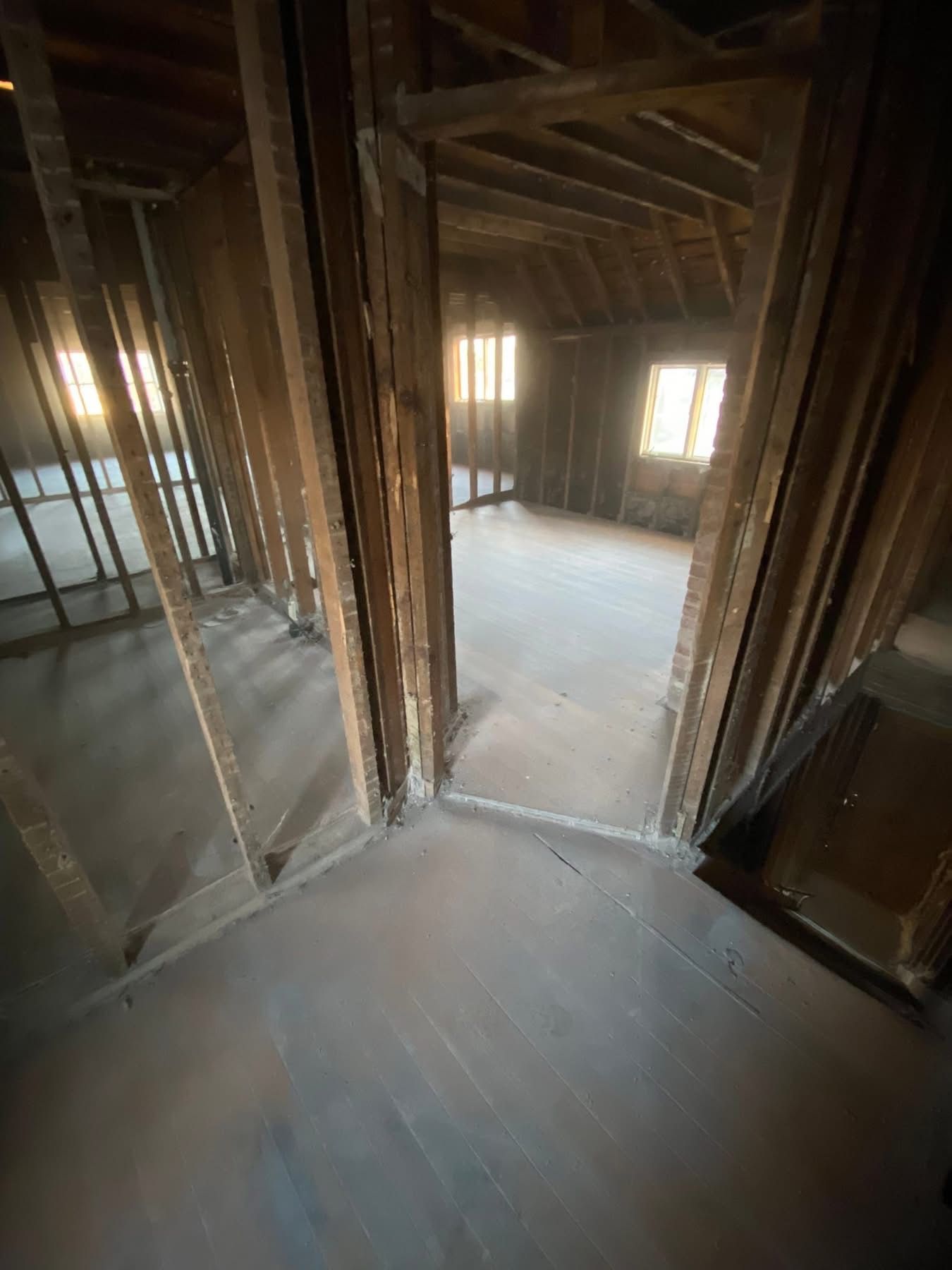 Interior view of an unfinished attic space with exposed wooden framing and doorways.