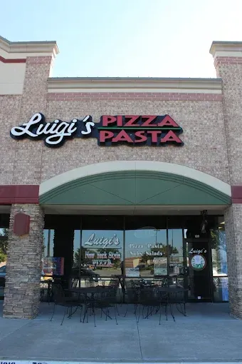 Pizza Parlor storefront, red neon sign, brick building, people eating inside, open sign.
