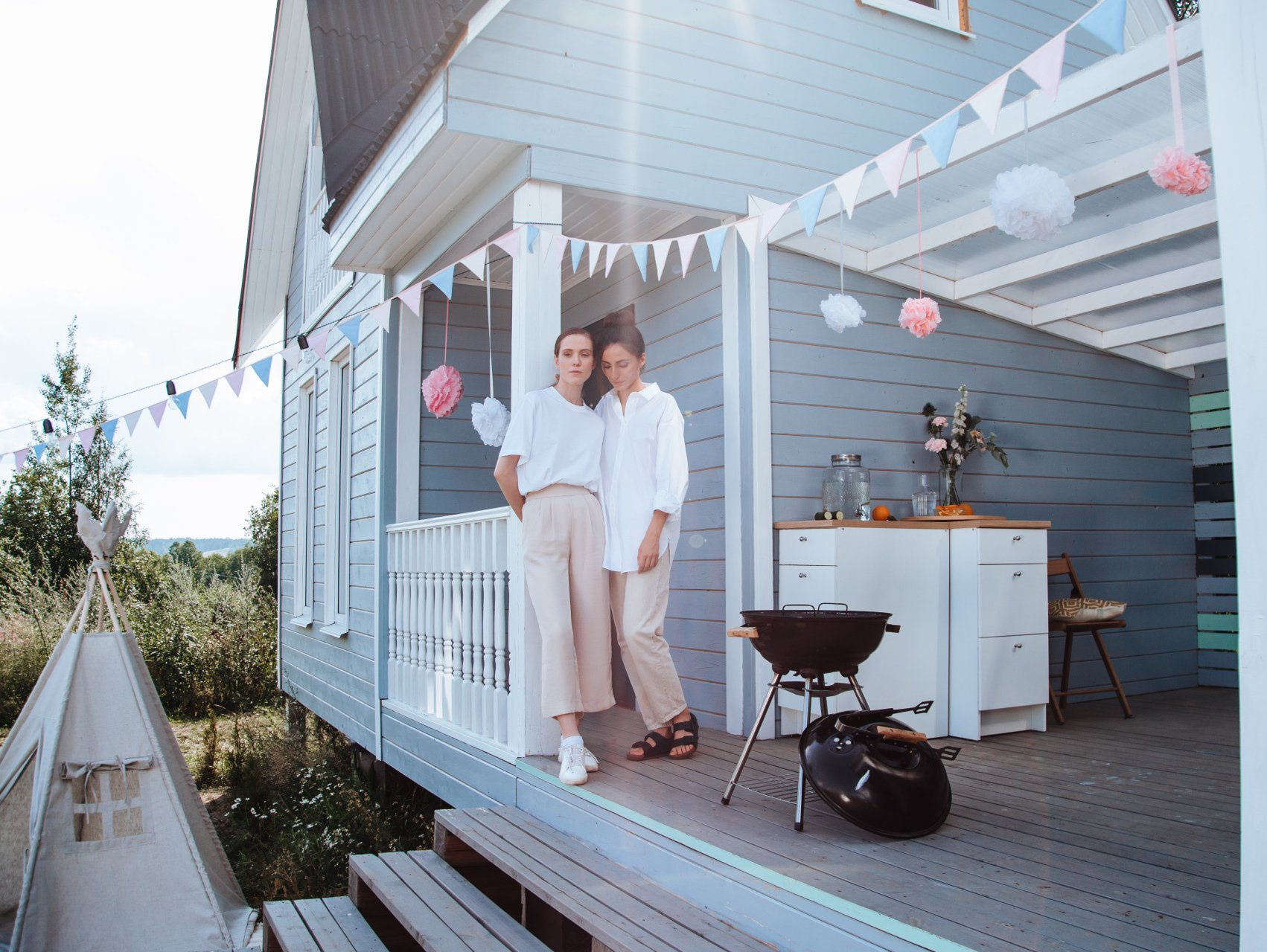 Two women are standing on a porch of a house.