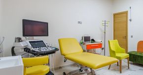 Un cabinet médical avec un lit jaune, des chaises et un appareil à ultrasons.