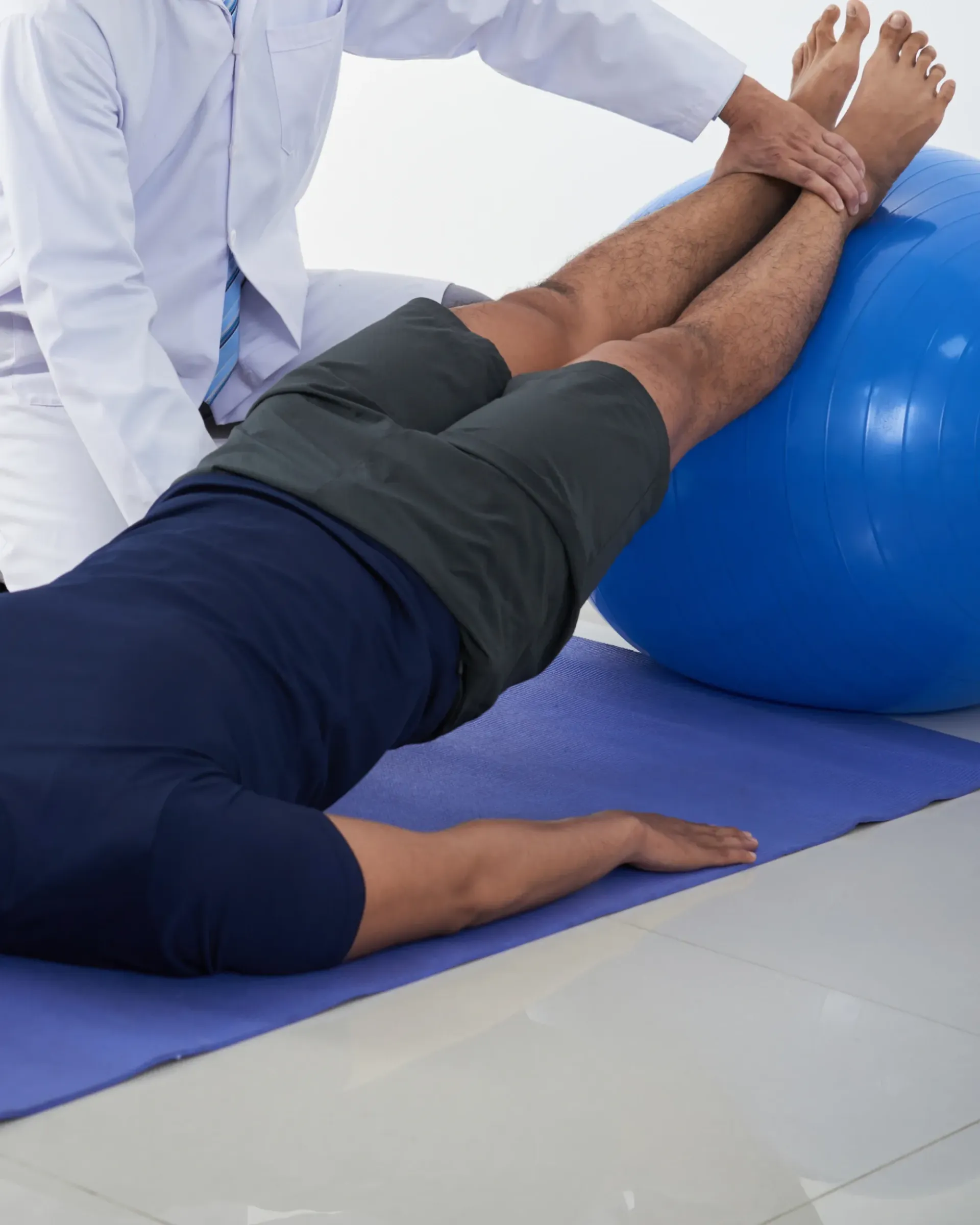 Un homme est allongé sur un tapis de yoga avec ses jambes sur un ballon d'exercice bleu