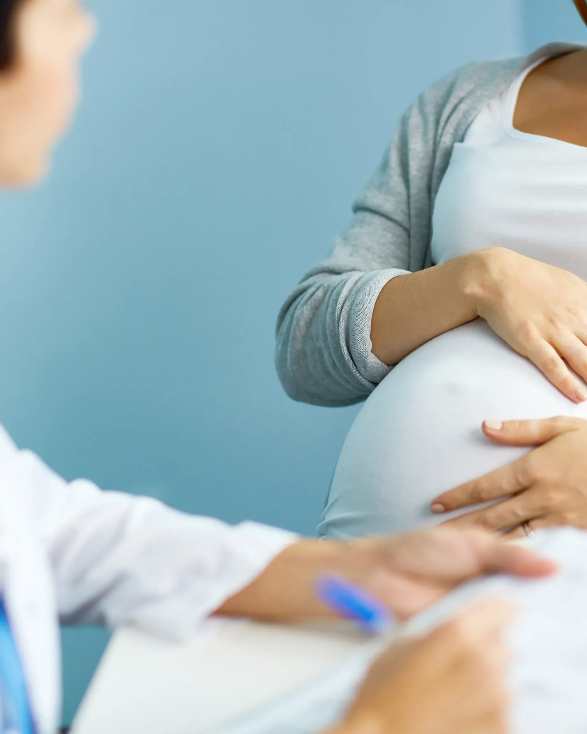 Une femme enceinte est assise à une table et parle à un médecin.