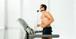 Un homme court sur un tapis roulant avec un masque à oxygène sur le visage.