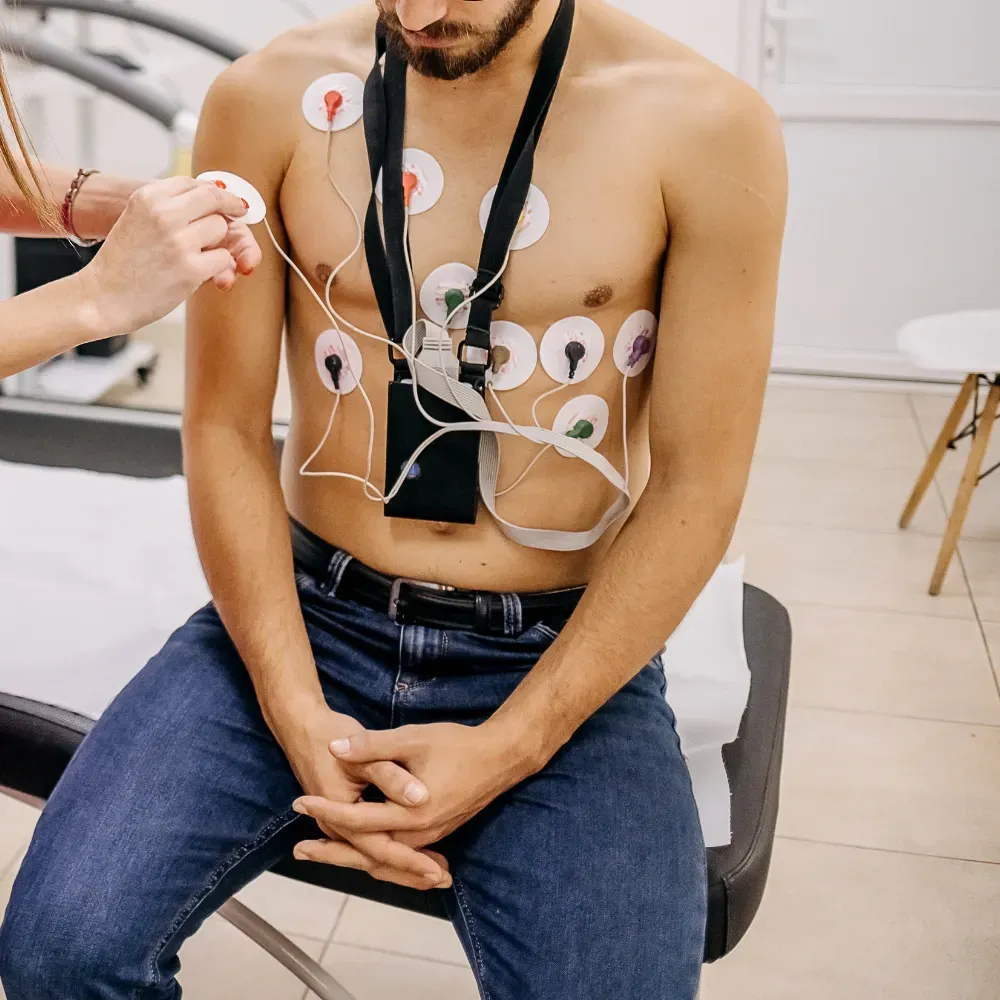 Un homme torse nu reçoit un électrocardiogramme d'un médecin.