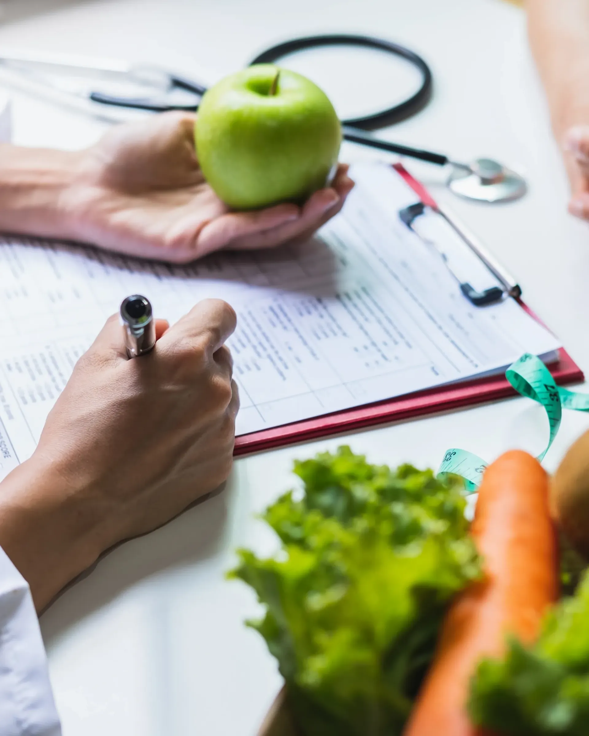 Une personne tient une pomme et écrit sur un presse-papiers
