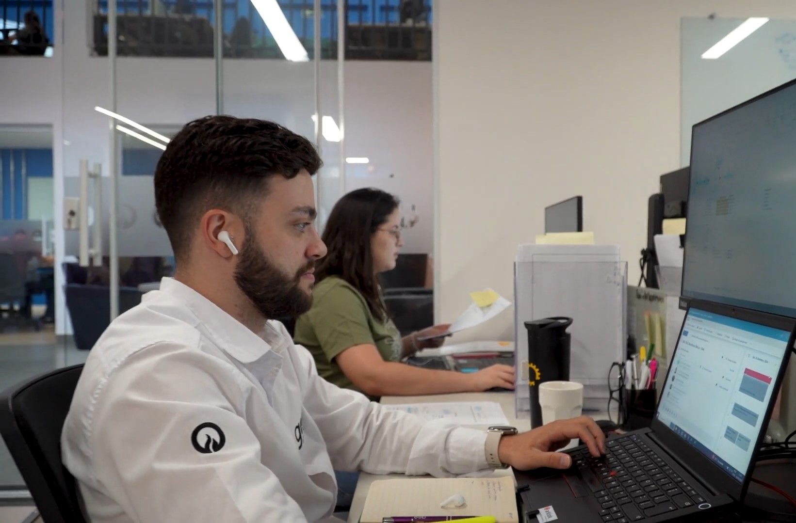 Um homem e uma mulher estão sentados em uma mesa em frente a um laptop.