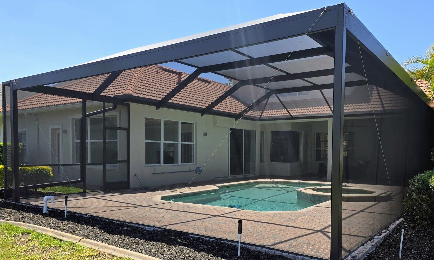 Woman in straw hat smiles, holding wine glass near a lake.