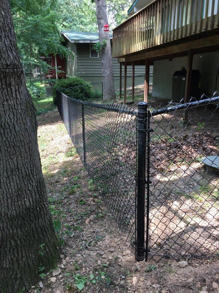a black chain link fence with a bird feeder in the background