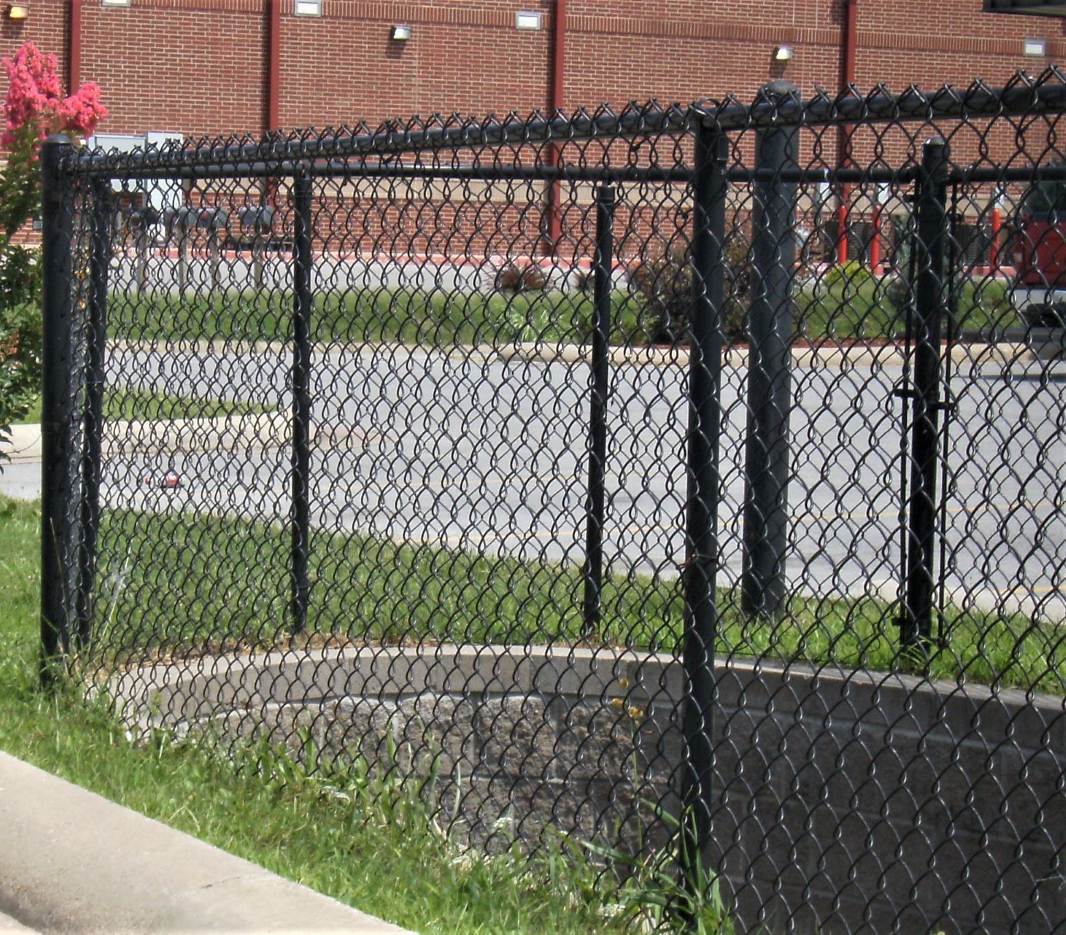 A black chain link fence with a brick building in the background