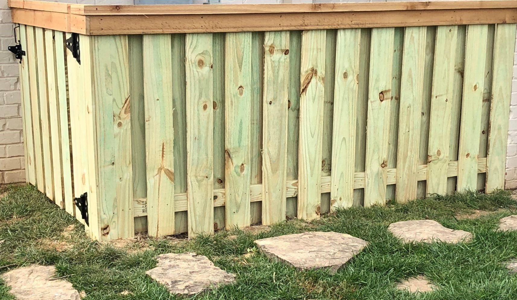 A wooden fence is sitting on top of a lush green lawn.