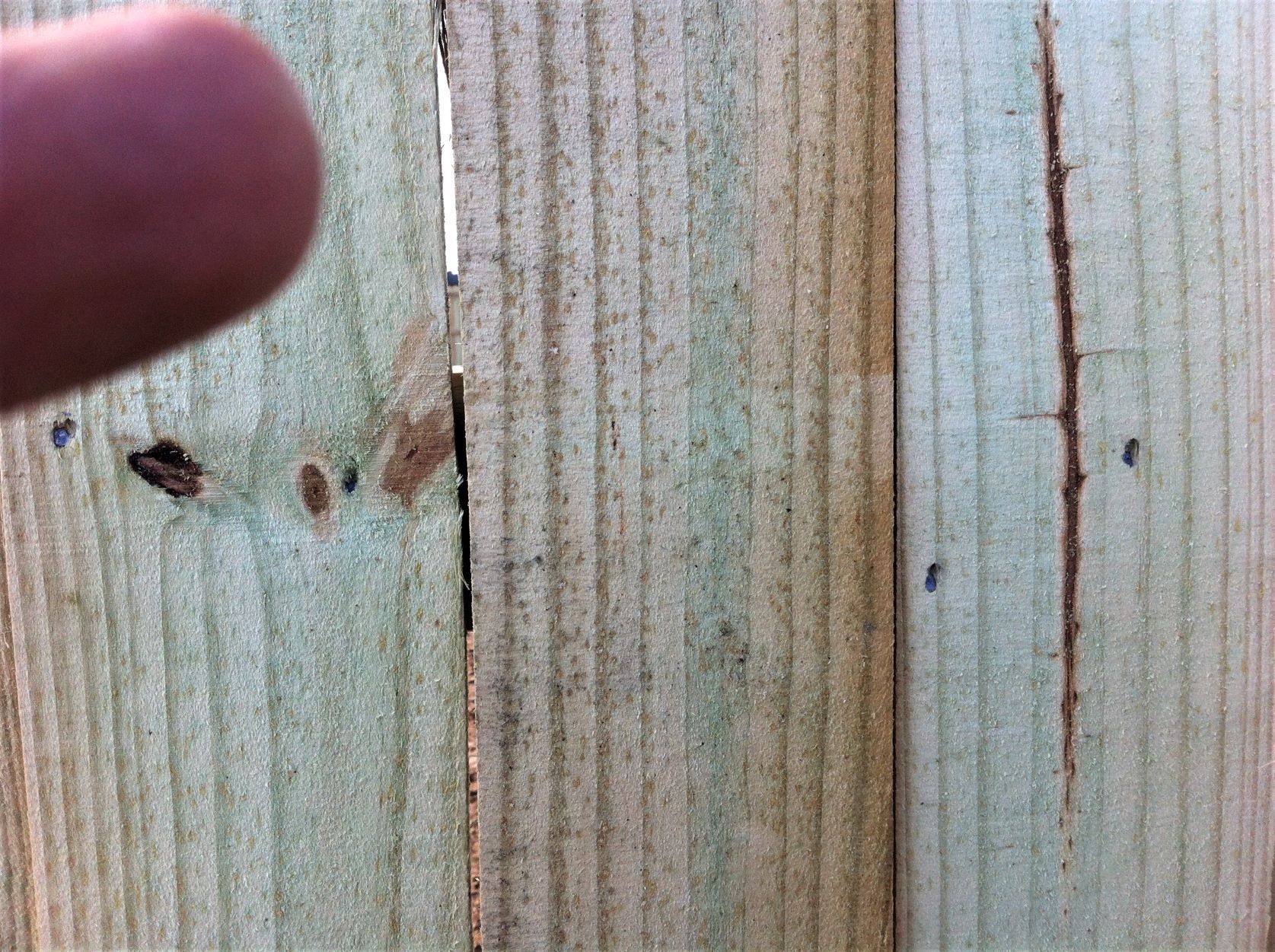 a close up of a wooden fence with holes in it