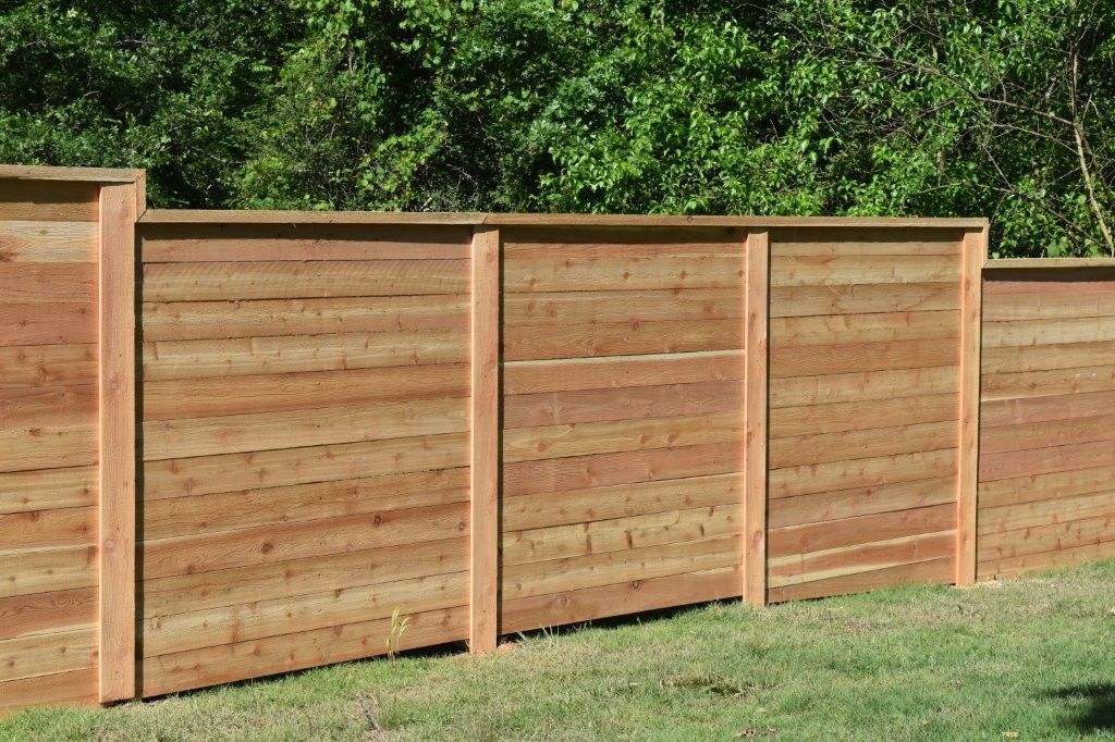 A wooden fence is sitting in the middle of a lush green field.