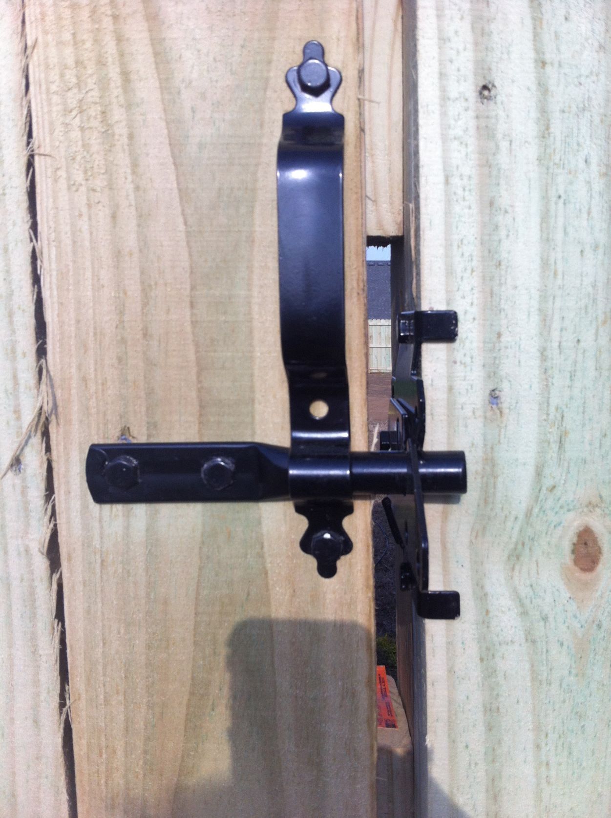 a black latch is attached to a wooden fence