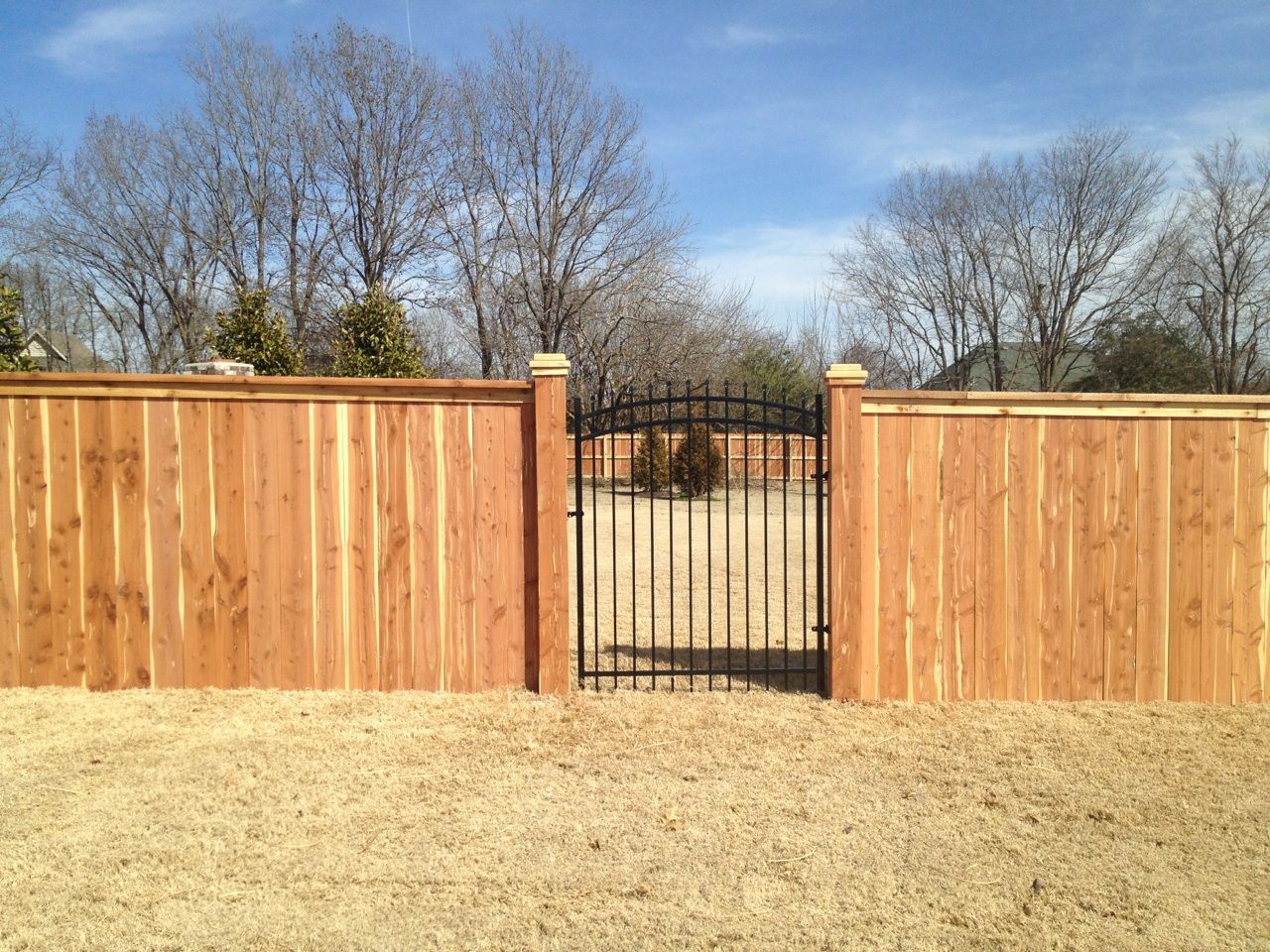 a wooden fence with a black metal gate in the middle