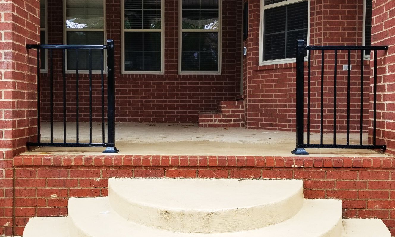 a brick house with stairs and a black gate