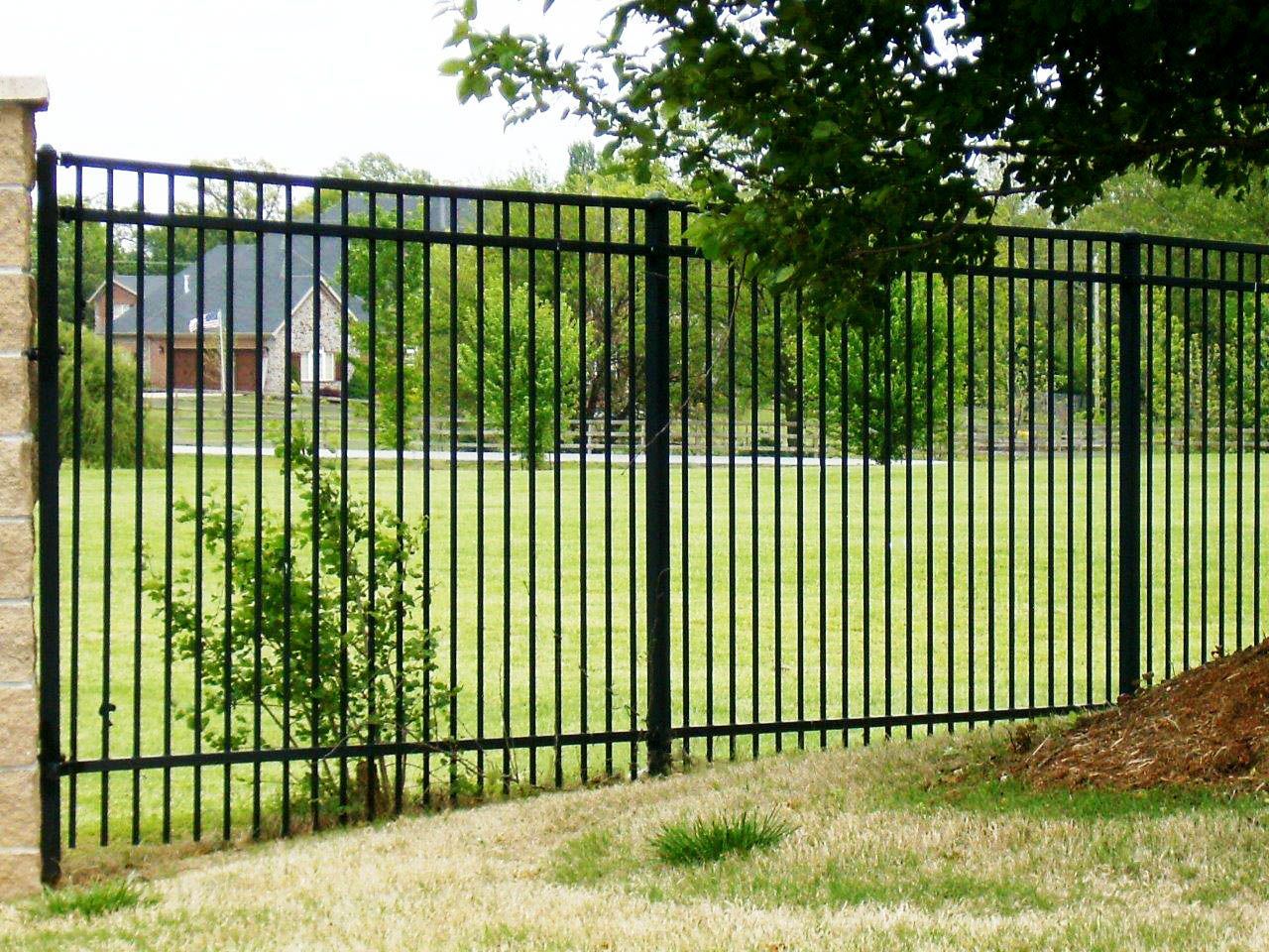 a black metal fence surrounds a lush green field