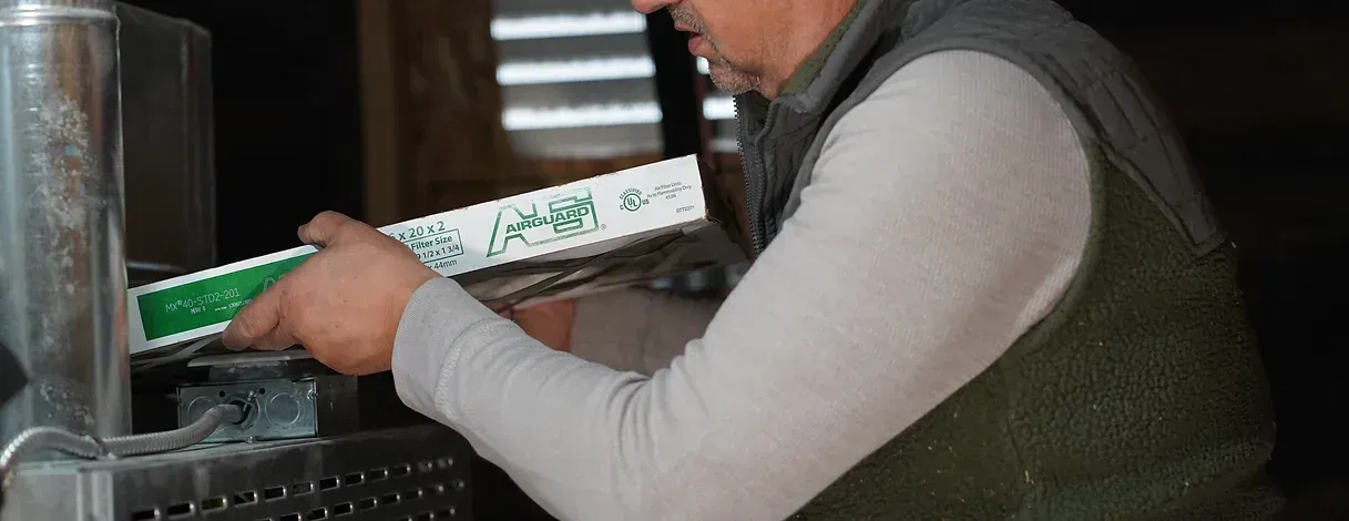 A man is cutting a piece of plastic with a saw.
