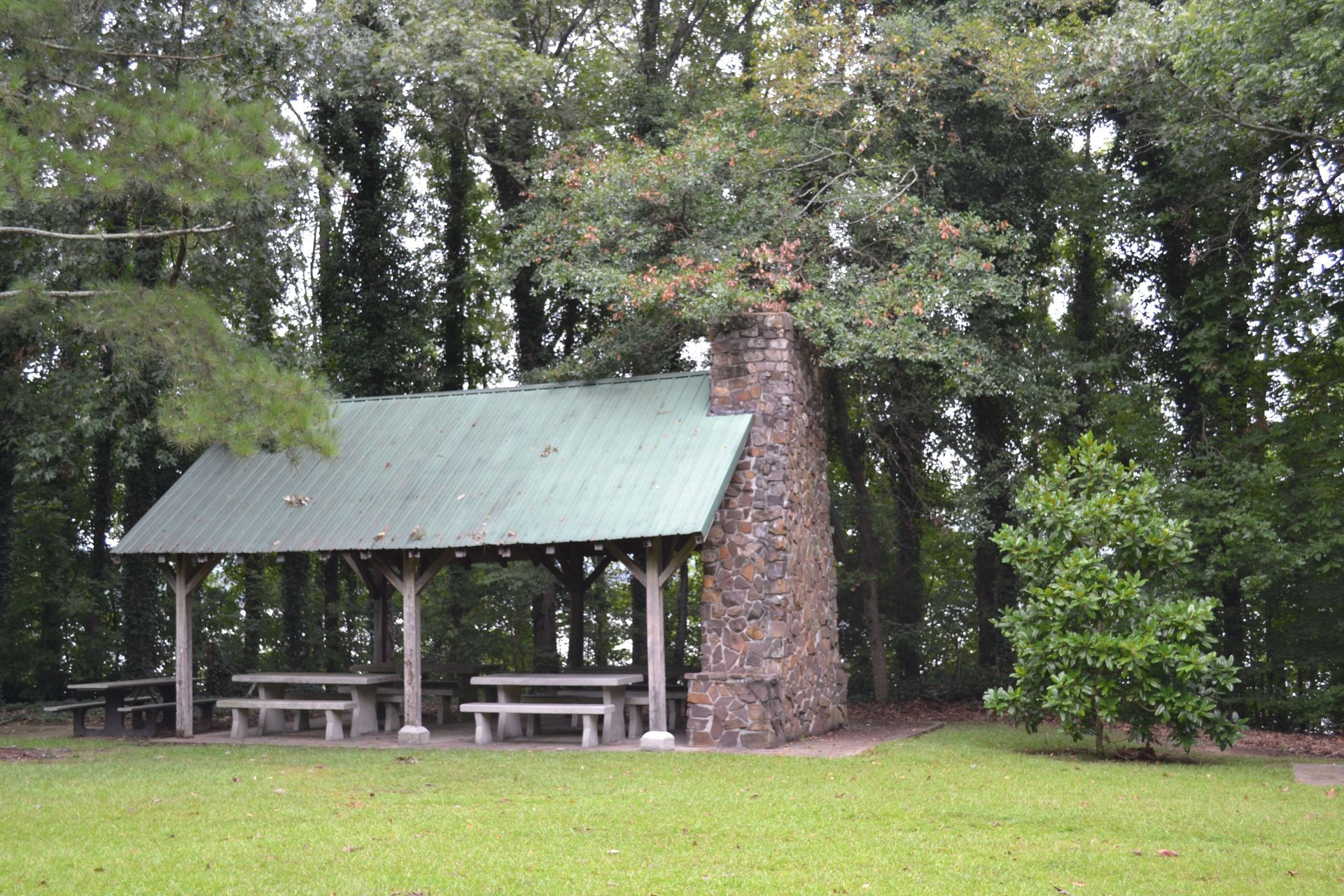 A stone structure resembling a kiln in a grassy park setting, with a picnic table in the foreground.
