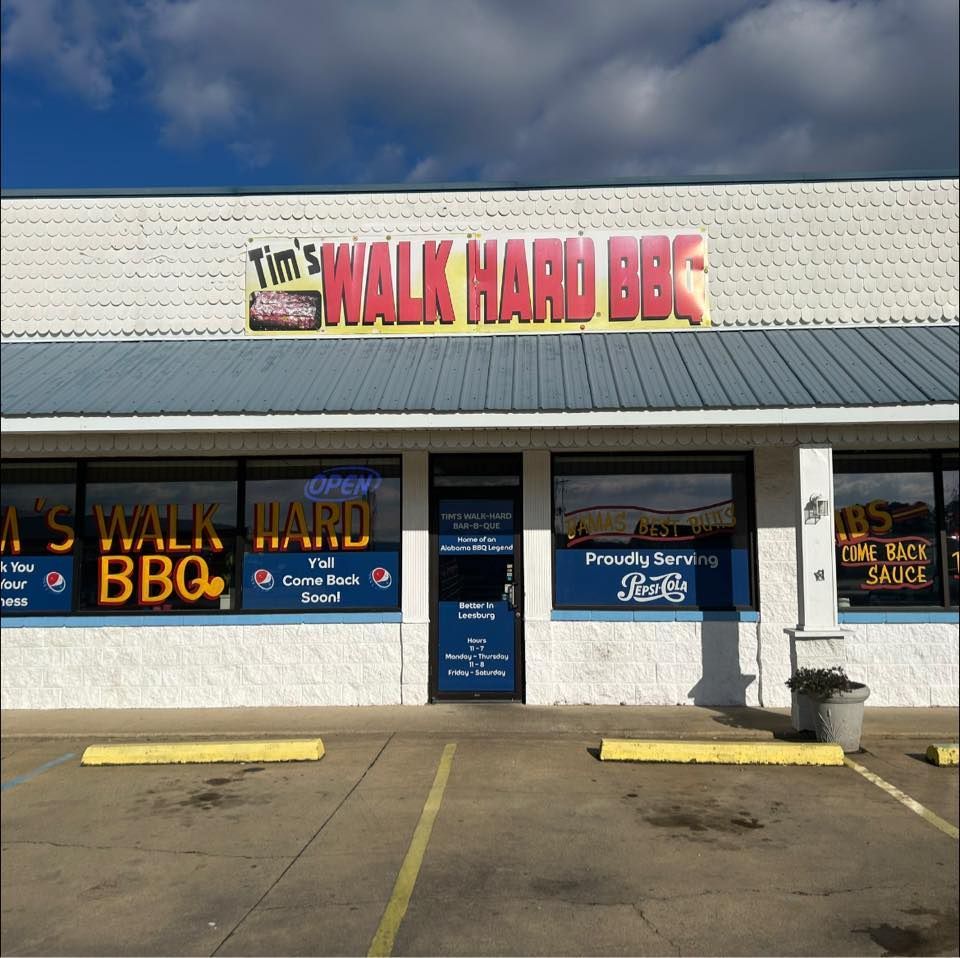 Tim's Walk Hard BBQ restaurant exterior with a sign and blue and yellow details under a partly cloudy sky.