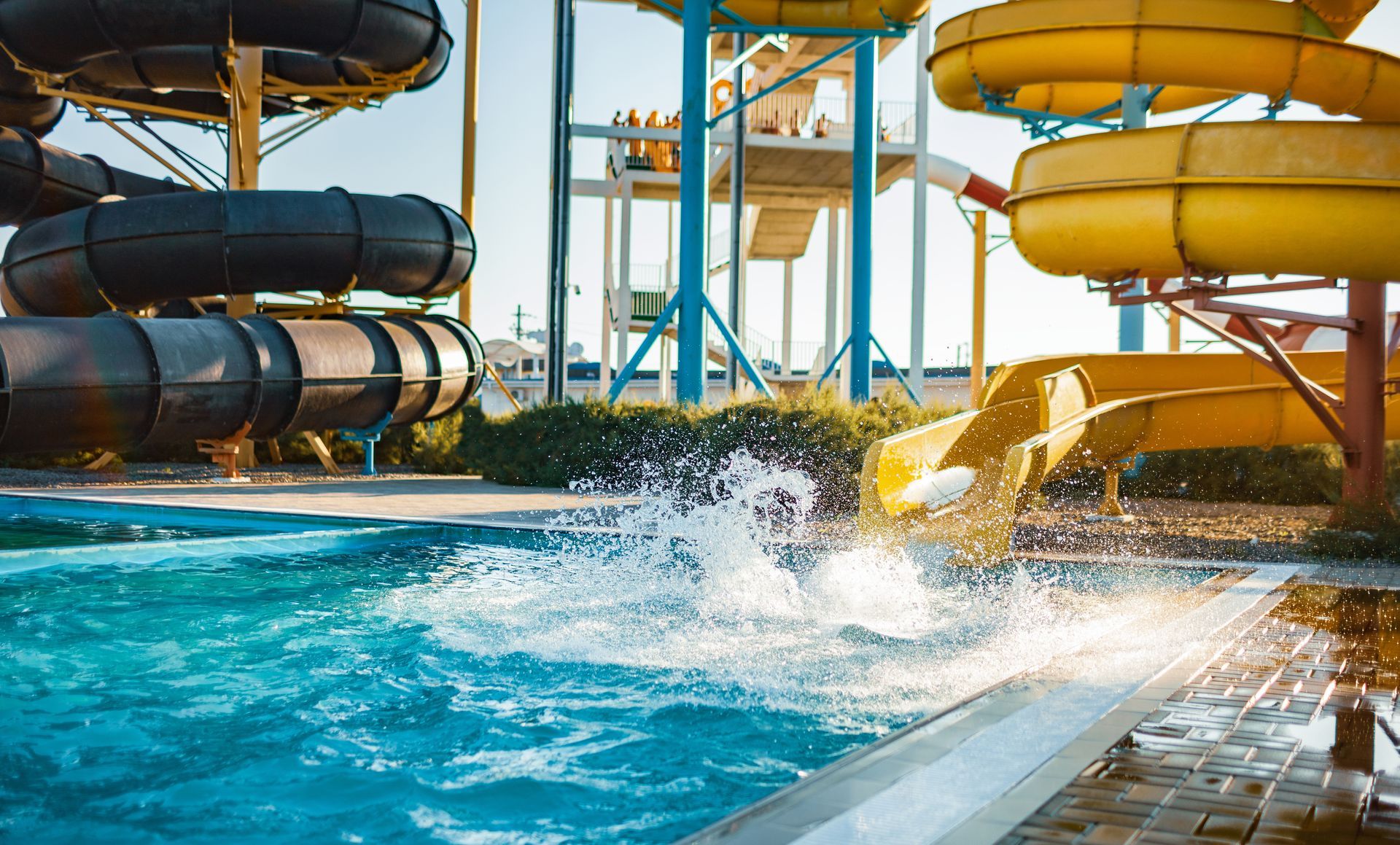 Water park with multiple colorful slides emptying into a pool, bright sunlight.