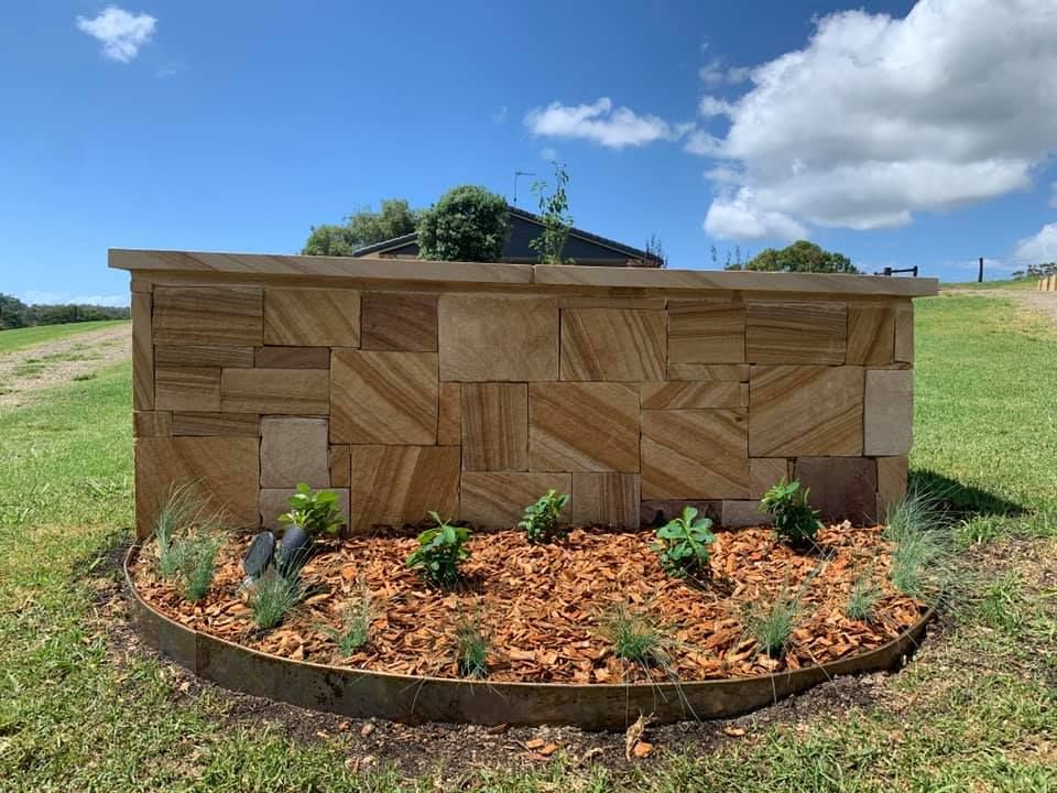 A Tan Stone Feature Wall Set in A Grassy Yard — Creative Landscapes Coffs Harbour in Sawtell, NSW