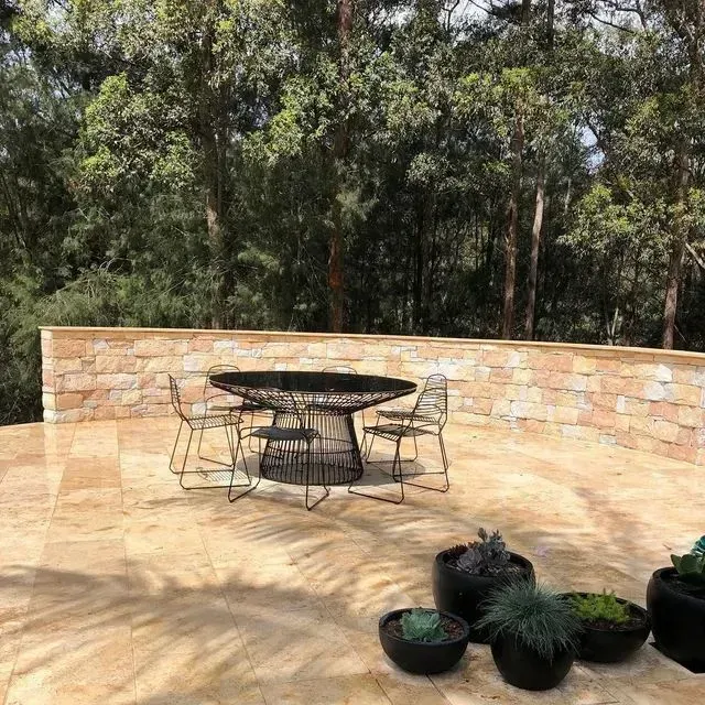 A Circular Outdoor Dining Table with Chairs Sits on A Paved Patio — Creative Landscapes Coffs Harbour in Woolgoolga, NSW