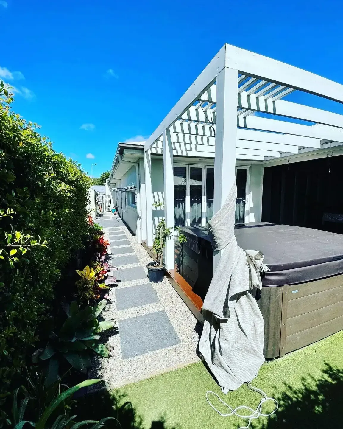 A Backyard Patio with A White Pergola Over a Covered Hot Tub — Creative Landscapes Coffs Harbour in Korora, NSW