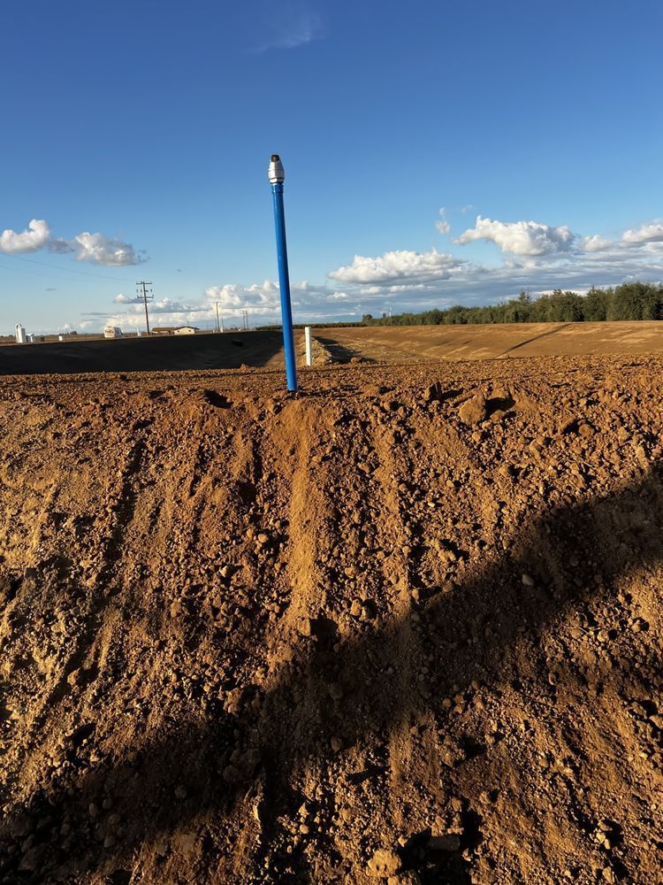 Blue utility post in a muddy construction field under a partly cloudy sky
