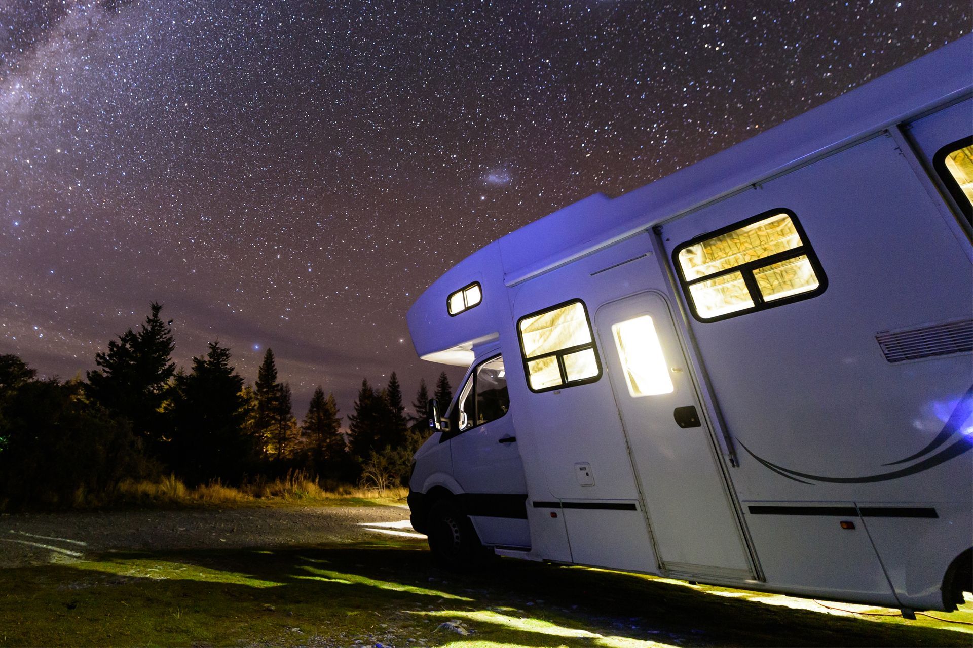 White RV is Parked Under Starry Night Sky