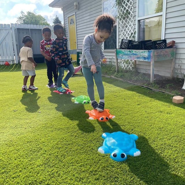 A group of children are playing with toy turtles on the grass.