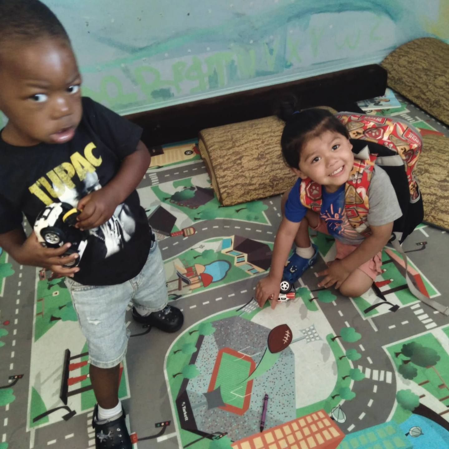 A boy wearing a tupac shirt holds a toy car