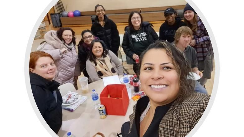 A group of women are sitting around a table taking a selfie.