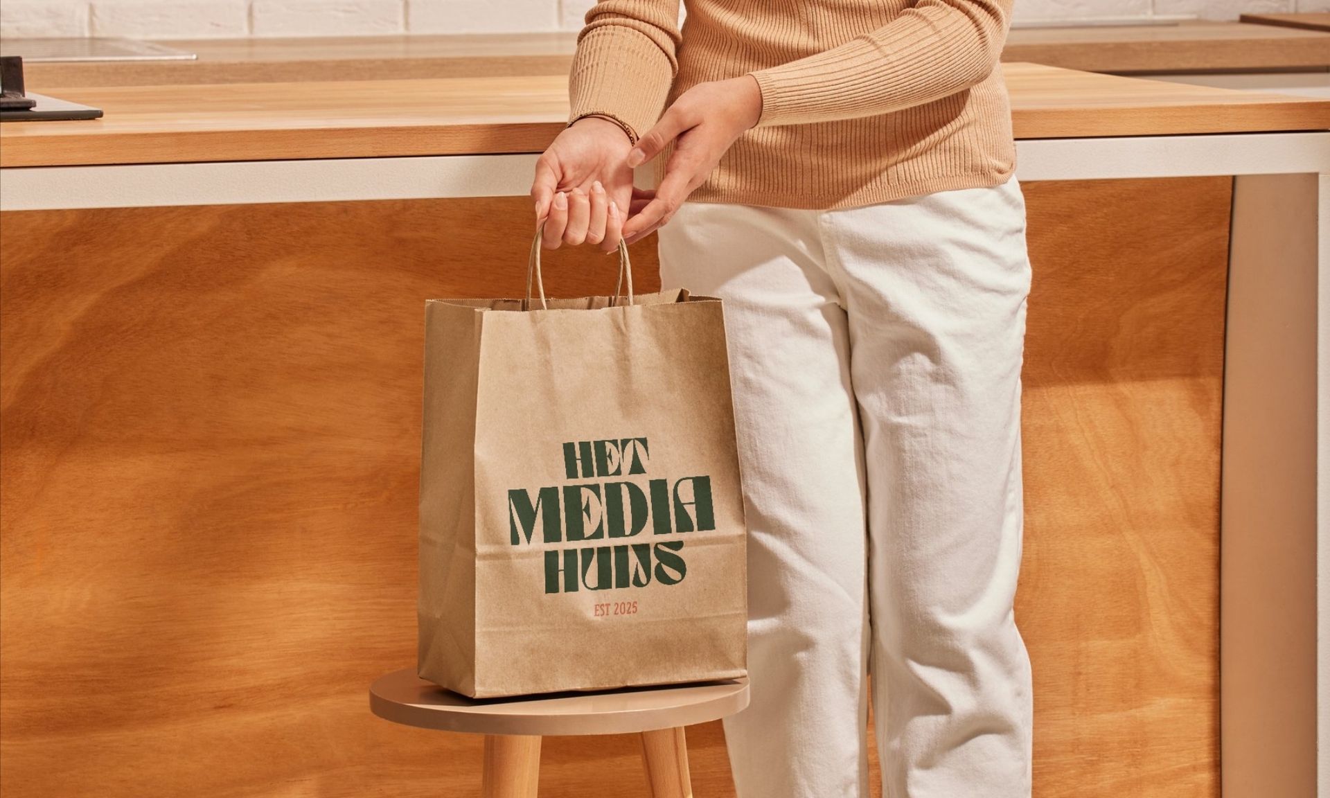 Een vrouw houdt een papieren zak vast waarop staat: met media huijs.