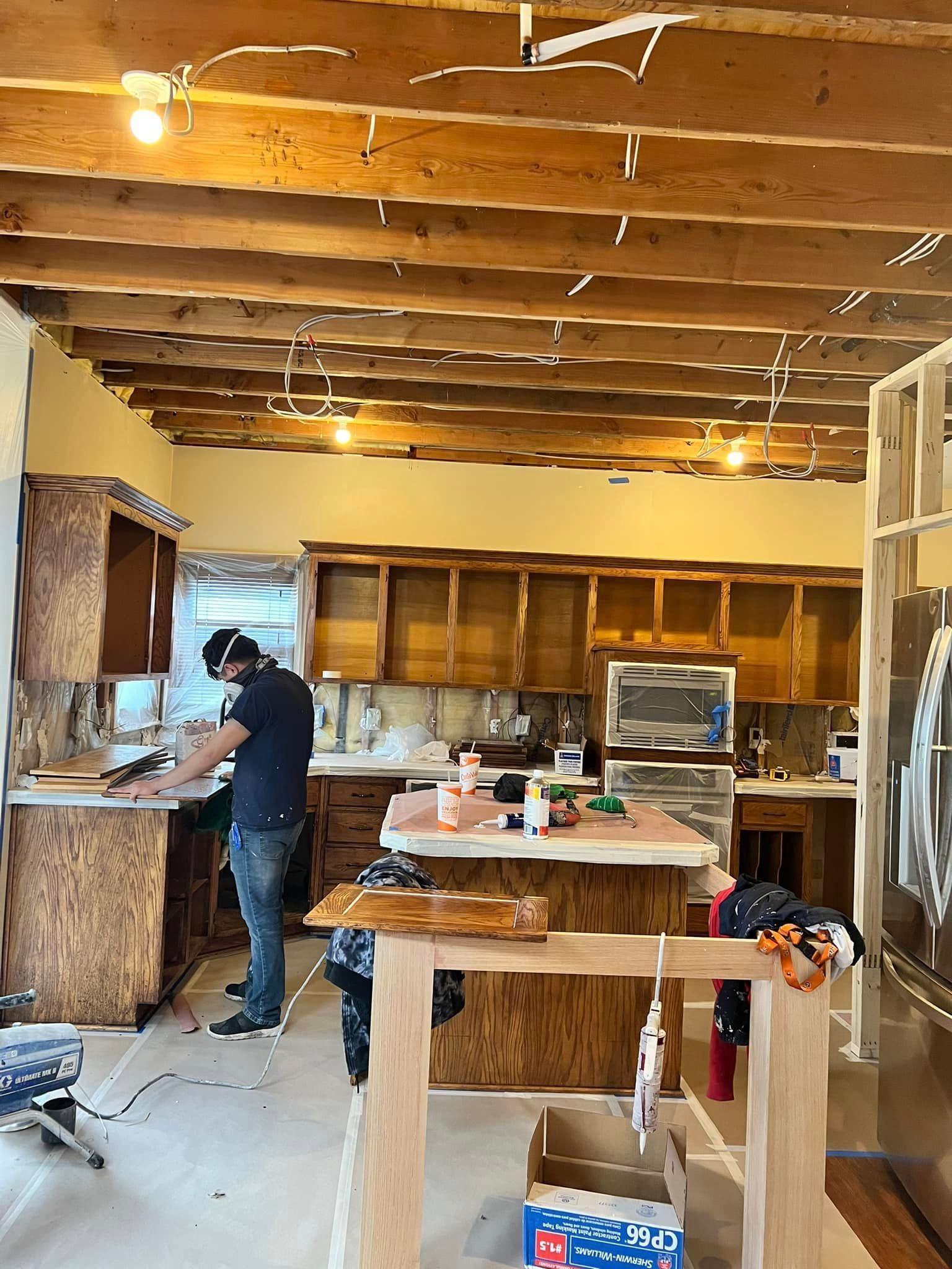 A Man Is Working In A Kitchen Under Construction – Olathe, KS - JJR Painting